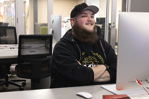 A student smiles by his Mac in the Mac lab