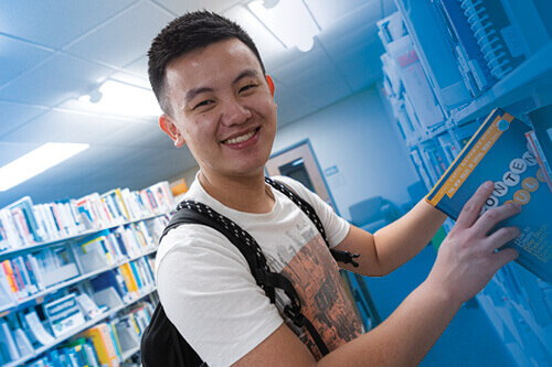 A student chooses a book in the Library