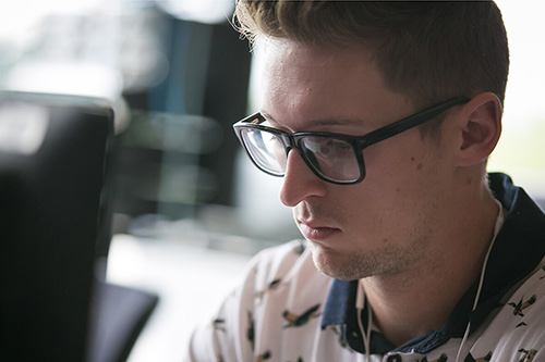 A student with glasses views a computer monitor