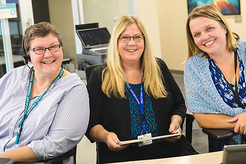 Three staff members smile at the front desk