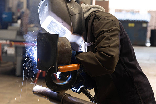 A student wears a mask and welds a part