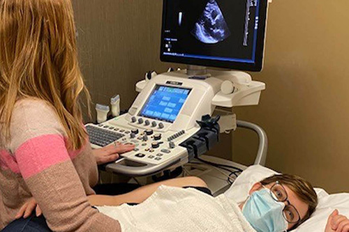 Student using echocardiography equipment.