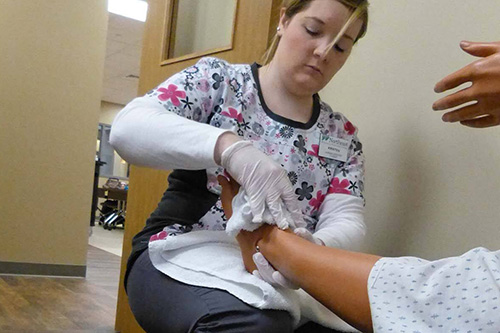 A personal care worker massages the leg muscles of a patient