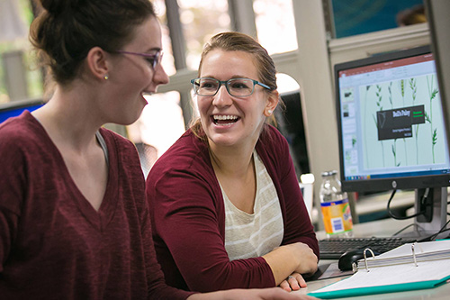 Two students work on event planning on a computer