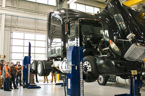Students work on a semi truck on a lift in the Transportation Center