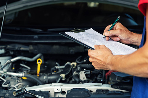 An auto mechanic checks issues off of a list