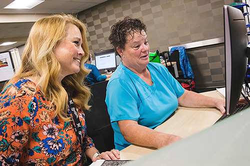 Two employees work on a computer together