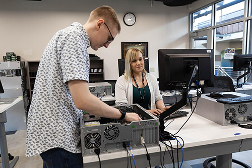 A student adds hardware to a computer in a lab