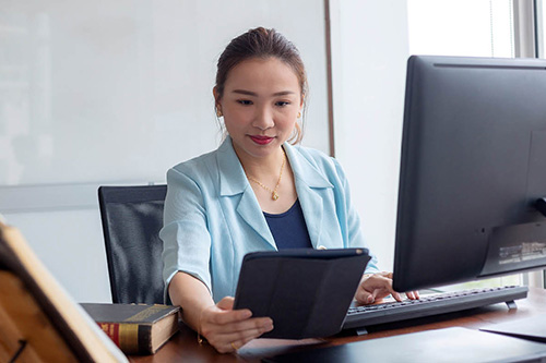 A woman consults a legal manual while working on the computer