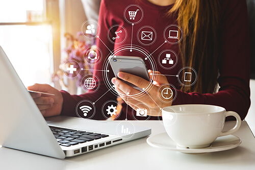 A woman works on social media and digital marketing on her phone and laptop