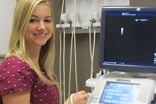 A nurse stands next to a sonography machine