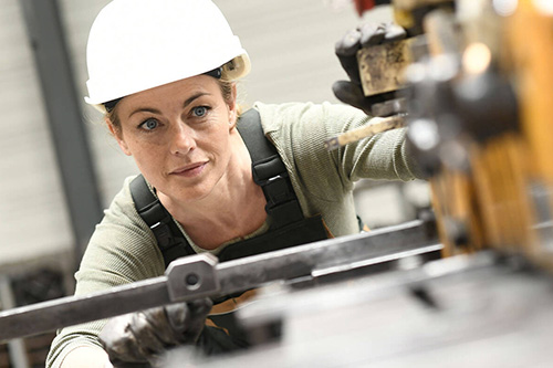 A woman works on a machine in a hardhat