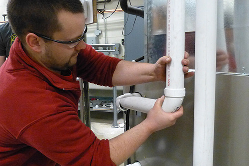 A man installs PVC pipes in a home