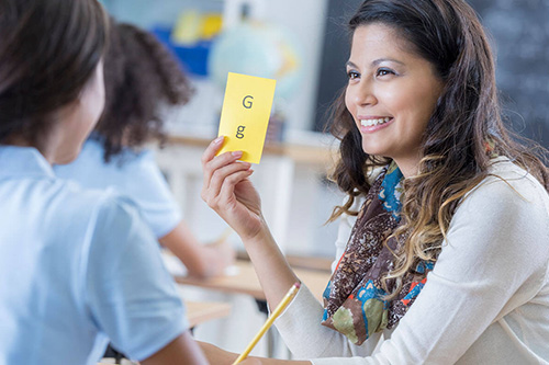 A teacher holds up a flashcard to a child