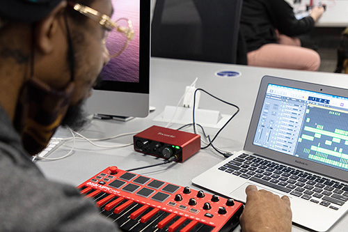 A student edits audio files after recording music from a keyboard