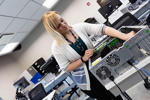 A woman swaps out hardware on a PC