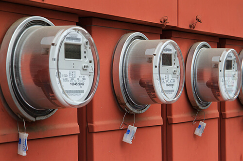 Three utility meters on orange siding