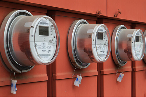 Three utility meters on orange siding