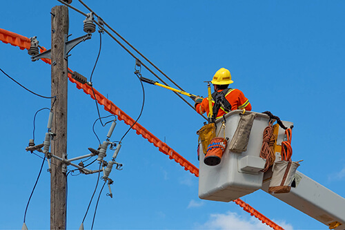 A utility worker accesses power lines from a lift