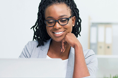 A woman in glasses reads text on her computer