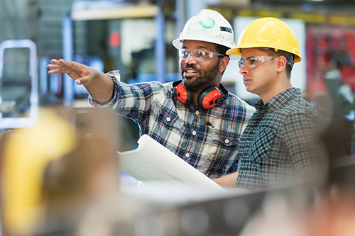 Two men consult plans in a manufacturing plant