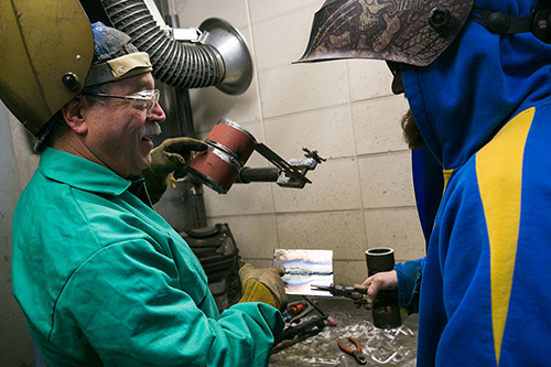 An instructor advises a student on the quality of a weld