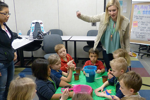 Two teachers work with young children at a table