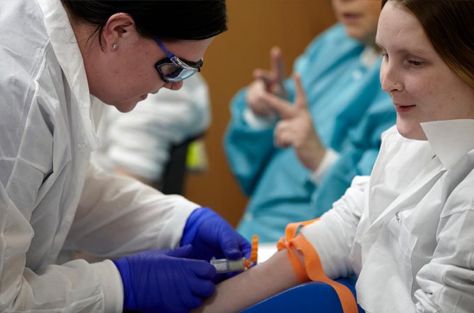 Nursing student draws blood from a volunteer
