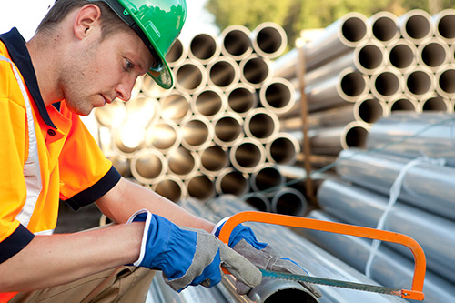 A worker cuts ductwork to fit