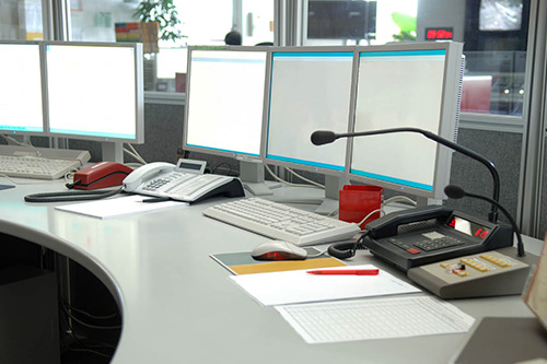 A dispatch station with microphones, telephones and multiple computer screens