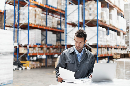 A worker examines inventory in a warehouse