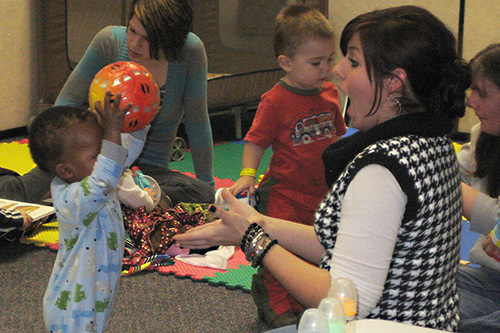 An early childhood teacher catches a ball from a toddler