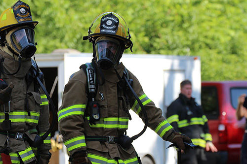Two fire medics wear protective gear at the scene of a fire