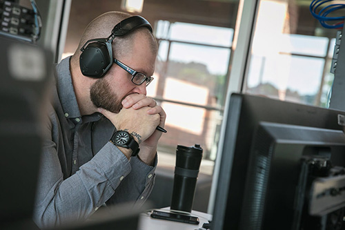 A programmer wears headphones and leans in to look at a monitor