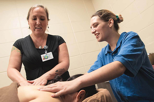 An instructor and a massage therapy student give a massage to a patient