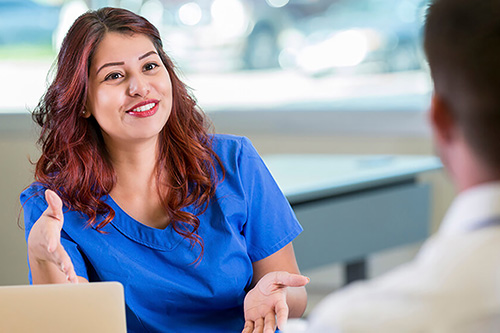 A nurse speaks with a health care administrator at a desk