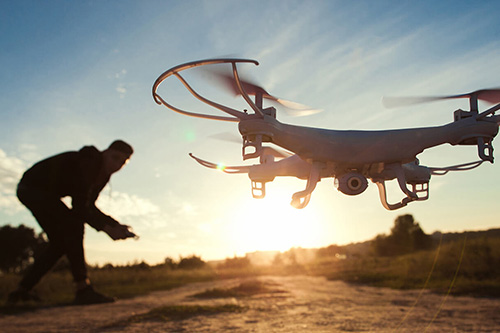 A man flys a drone in front of the setting sun