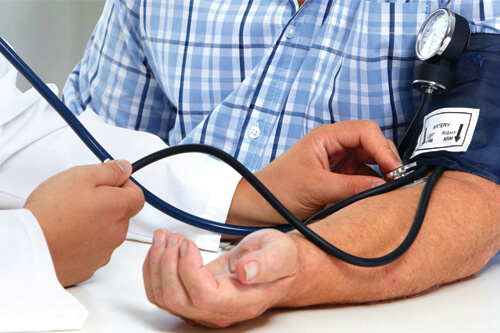 A health care worker checks a patient's blood pressure