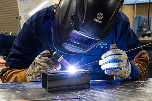 A student welds with a mask on