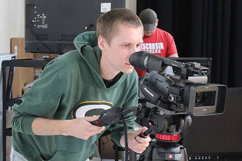 A student uses a camera to videotape a commercial