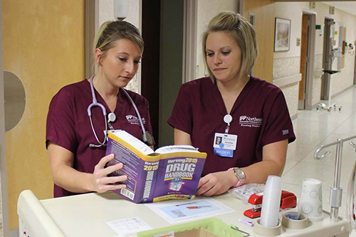 Two nurses consolut a prescription medication handbook