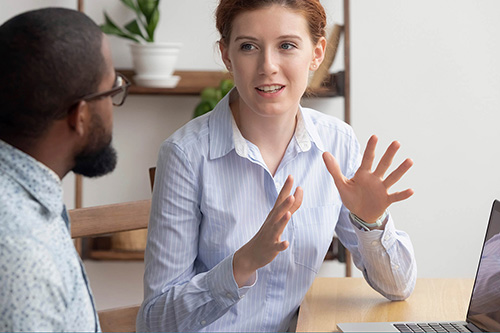 Two employees have a discussion in a meeting room