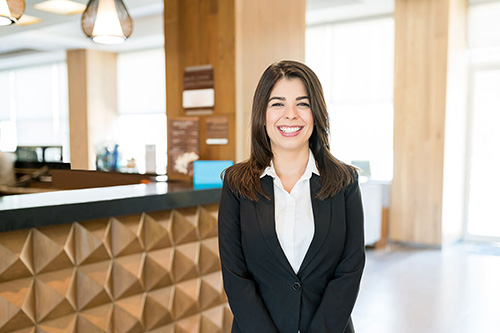 A hotel manager greets guests at the front desk