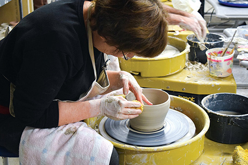 A student works clay on a potters wheel