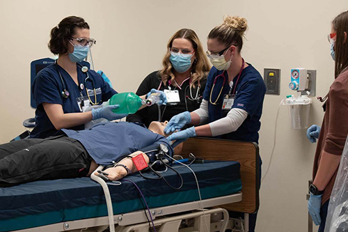 Three students revive a patient simulator