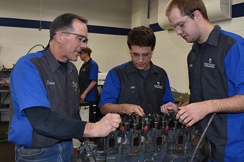 Students work with an instructor on a diesel engine
