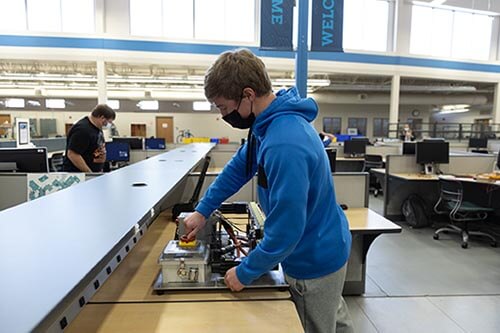 Student in a mask works on a control system