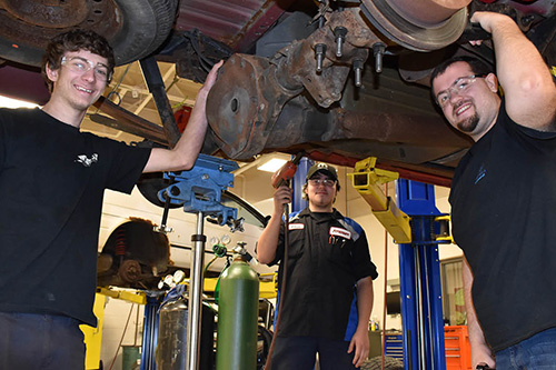 Students work under a car on a lift