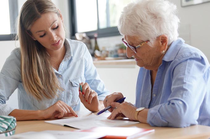 Gerontology worker assists elderly woman with paperwork