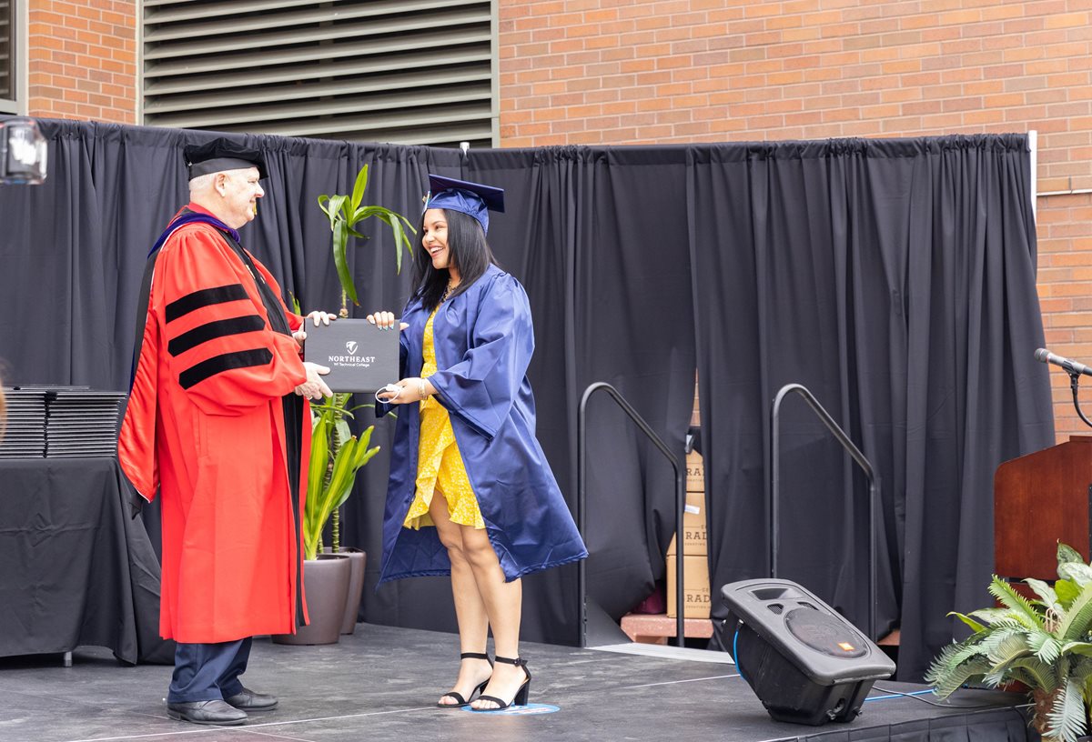 A student in cap and gown receives an award from the President.